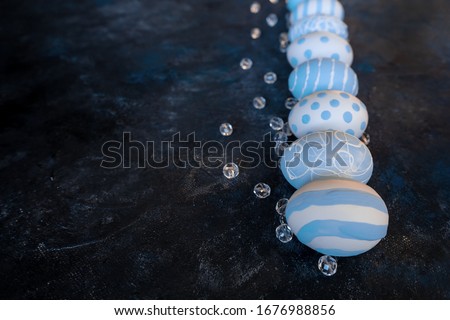 Spring Easter row of eggs in different patterns, polka dots and stripes on dark textural background with beads. Celebration Festive design. Copy space.