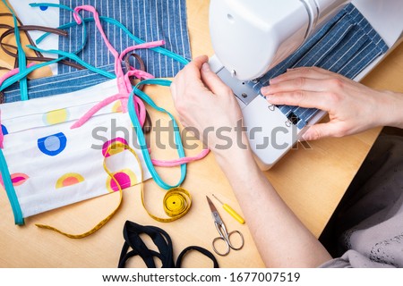 Woman hands using the sewing machine to sew the face mask during the coronavirus pandemia. Domestic sewing due to the shortage of medical materials. Royalty-Free Stock Photo #1677007519
