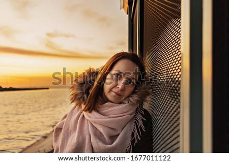 Close-up portrait of a woman at the bus stop on the background of the bay. Sunset on the Gulf of Finland. Springtime.