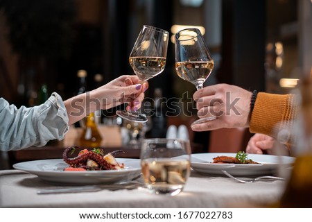 Romantic dinner. Couple cheers with white wine Royalty-Free Stock Photo #1677022783