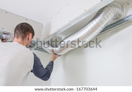 Man setting up ventilation system indoors Royalty-Free Stock Photo #167703644