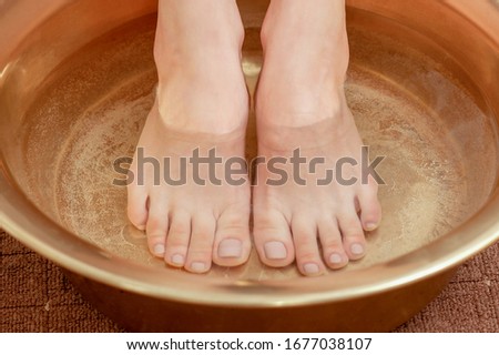 Feet of woman in bowl with water close up.