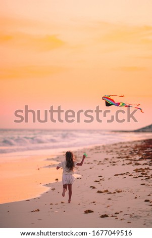 Little girl flying a kite on the beach