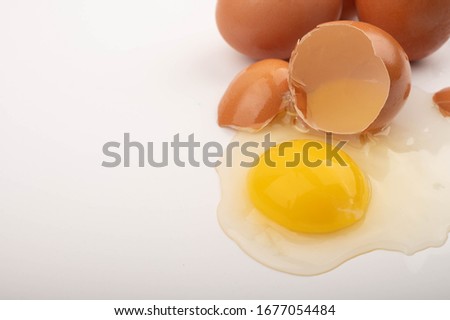 Broken chicken egg and scattered eggs on a white background. Close up.
