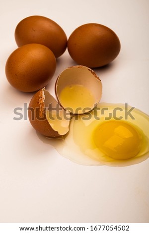 Broken chicken egg and scattered eggs on a white background. Close up.