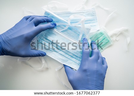 Doctor, nurse or scientist hand in blue nitrile gloves holding a medical face mask for protection against infection. Covid-19 coronavirus with stop sign Earth in medical mask quarantine 