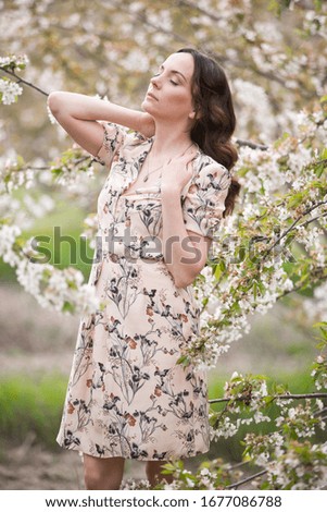 Elegant slender woman enjoys relaxing in the blooming cherry orchard. Holidays in the village