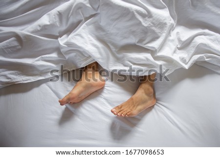 Feet Under Blanket Stock Photo, High Angle View Of People Sleeping In Bed With White Blanket Picture