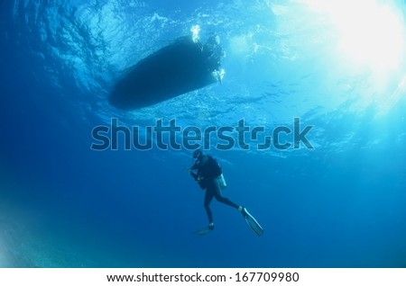 Boat and diver silhouette under water with beautiful sun ray, Hawaii.