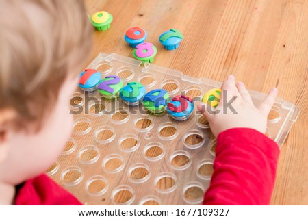 counting game. collect correct amount of caps by assigned number. little boy perform the task. early education. 