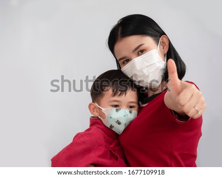 Portrait of mother and son are showing OK sign and wearing mask trying to protect from coronavirus epidemic over gray background.