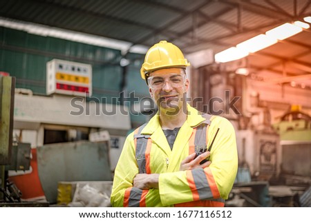 The factory engineer in a yellow uniform and wearing a yellow hat hit the post in the factory.