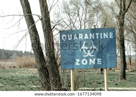 Quarantine zone sign. Blue metal sign with the inscription "Quarantine Zone". A warning sign among the trees in front of the infected area