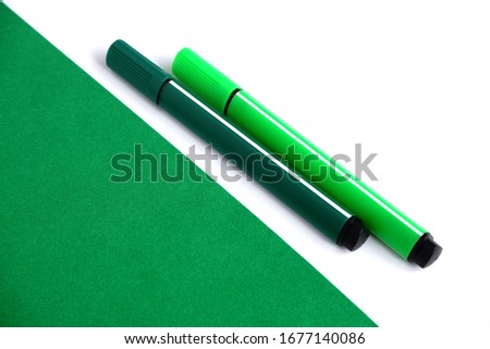 Two markers - green and light green on a green and white background. School supplies. Suitable for advertising background