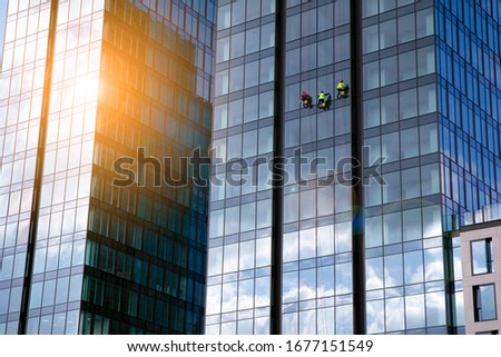 Office building glass facades on a bright sunny day with sunbeams in the blue sky. Abstract view of a skyscraper with sunlight