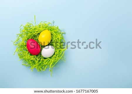 Cute Easter composition. Paper nest with multicolored easter eggs on blue background. Top view. Copy space - Image