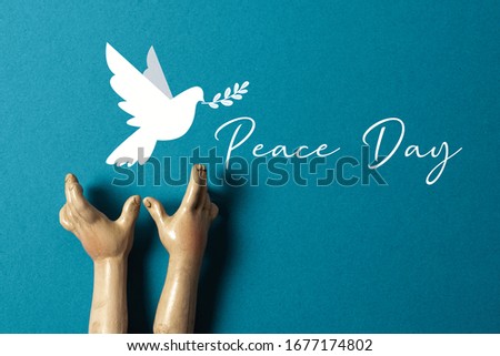 Ceramic hands launch the white dove of peace with olive branch on blue background.
International Peace Day or World Peace Day concept.