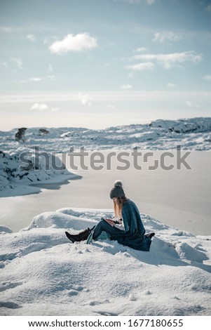 Beautiful lifestyle photo of young woman reading outdoors to enjoy sunny winter morning in mid Norway