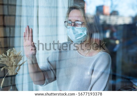 woman stands and looks out the window, self-isolation, prevention of corona virus Royalty-Free Stock Photo #1677193378