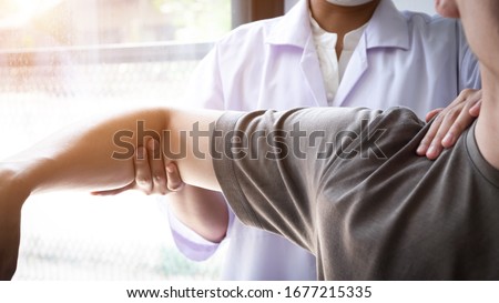 Therapist treating a male injured by shoulder impingement test, Physical therapy concept. Royalty-Free Stock Photo #1677215335