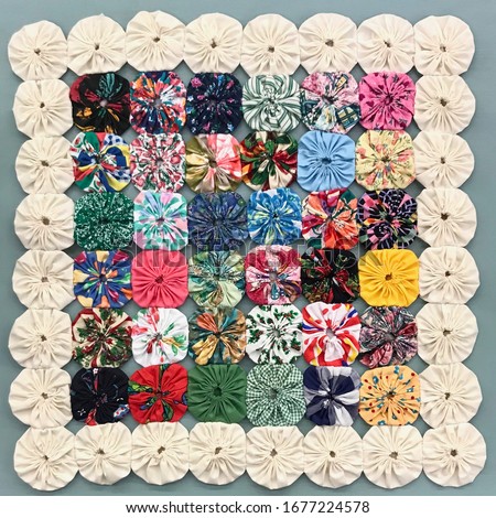 Quilt Button Style Yo Yo Flower Vintage Pattern in Colorful Fabric Arrangment Royalty-Free Stock Photo #1677224578