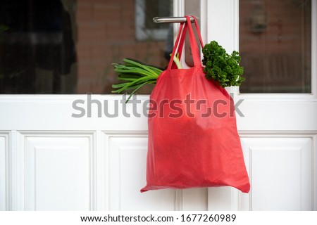 Shopping bag with goods and food is hanging at the front door, neighborhood help concept at quarantine time because of coronavirus infection, copy space, selected focus Royalty-Free Stock Photo #1677260989