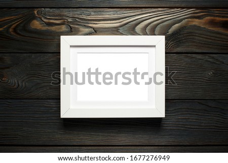 White horizontal frame hanging on dark wooden wall