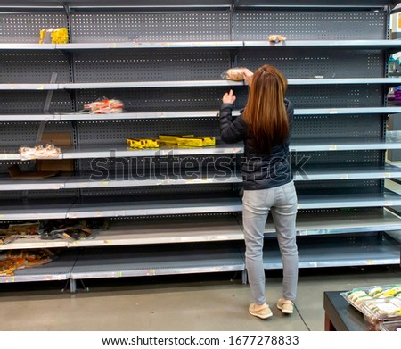 Woman shopping among empty shelves at a supermarket during coronavirus pandemic  Royalty-Free Stock Photo #1677278833