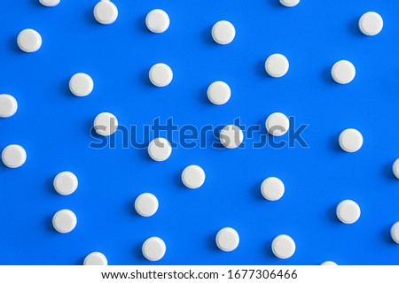many white pills on a blue background. medicines on the background, texture, pattern