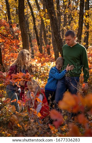 The family walks in the autumn forest and enjoys the autumn colors