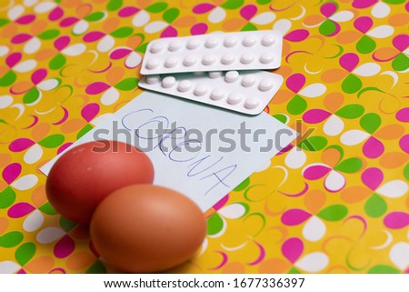 White pills and eggs on a custom yellow background. Paper with inscription CORONA. Easter during corona virus outbreak, covid-19 worldwide crysis in easter holiday time