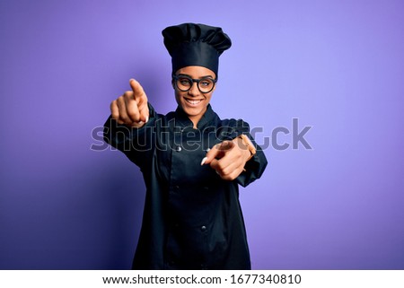 Young african american chef girl wearing cooker uniform and hat over purple background pointing to you and the camera with fingers, smiling positive and cheerful