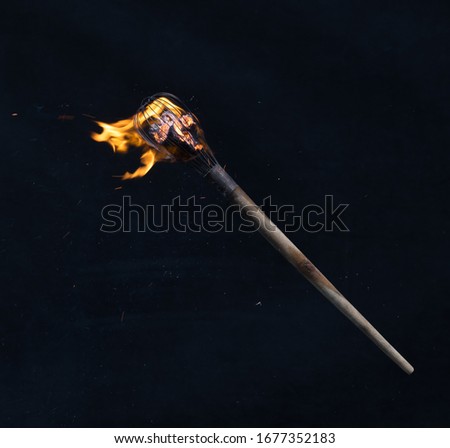wooden burning torch on a black background Royalty-Free Stock Photo #1677352183