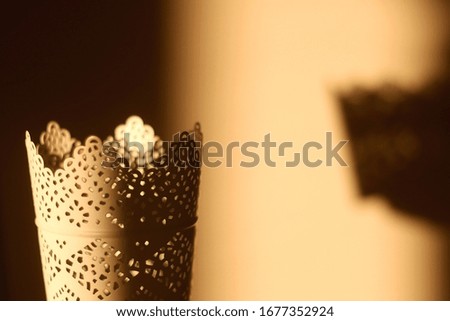Intricate candle holder, illuminated by warm sunset light. Selective focus.