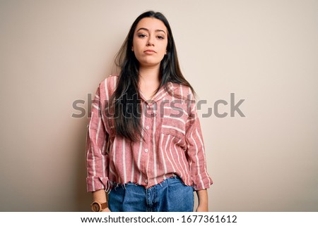 Young brunette woman wearing casual striped shirt over isolated background Relaxed with serious expression on face. Simple and natural looking at the camera.