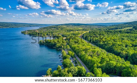 Keuka Lake surrounded by green trees during the summertime.  Royalty-Free Stock Photo #1677366103