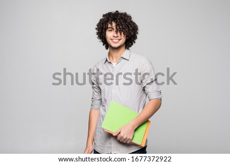 Young handsome curly student man with notebooks over isolated white background
