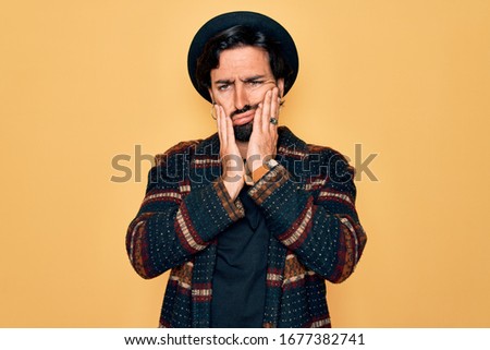 Young handsome hispanic bohemian man wearing hippie style and boho hat Tired hands covering face, depression and sadness, upset and irritated for problem