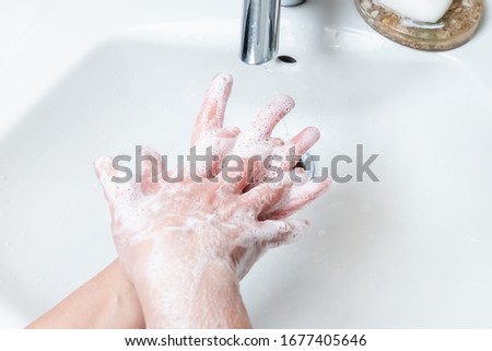 Washing hands with soap under the faucet with water
