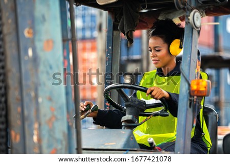 Female worker driving forklift in industrial container warehouse. Royalty-Free Stock Photo #1677421078
