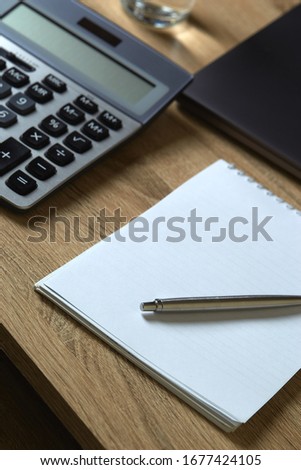 Remote work laptop calculator phone notepad with pen on the table