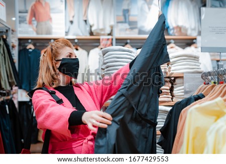 beautiful woman with phone bright pink shopping Mall coat with black protective mask on her face from virus infected air. concept of virus protection in the fashion, beauty, and shopping industries. Royalty-Free Stock Photo #1677429553