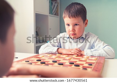 lovely little boy plays checkers