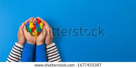 World autism awareness day concept. Adult and child hands holding puzzle heart on light blue background Royalty-Free Stock Photo #1677433387