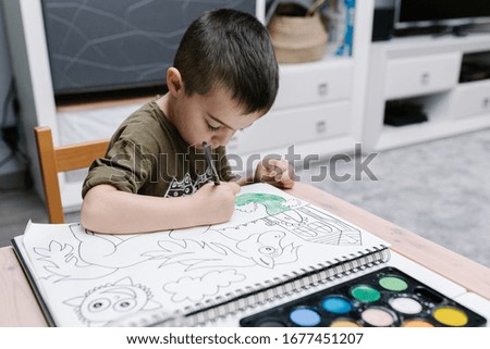 kid painting with water-colors at home during COVID-19 quarantine with his mother