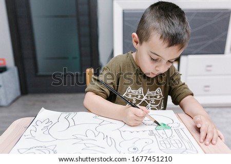 kid painting with water-colors at home during COVID-19 quarantine with his mother