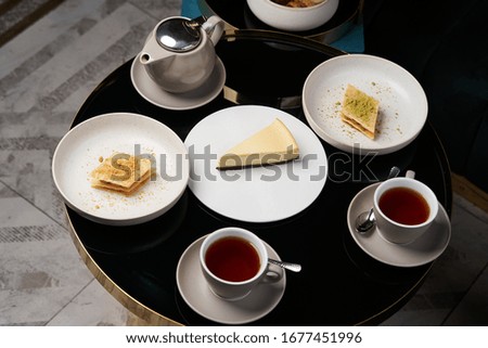 Sweets dessert cookies cake and teapot with cups. Afternoon tea with cake on restaurant table, close-up. Traditional tea ceremony.