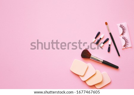 Makeup accessory with sponge, brushes,  applicators and eyelashes  onl pink background. Top view and Copy Space Flat Lay.