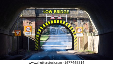 Direct view of a single lane tunnel, with yellow and black warning stripes, and lettering which states Low Bridge