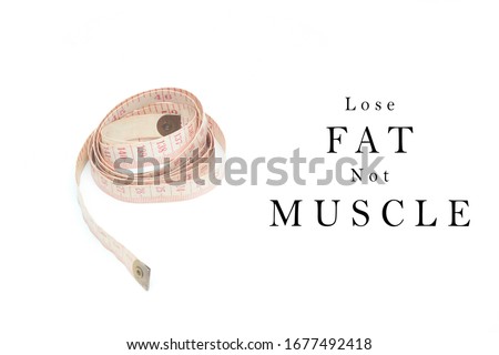 Healthy lifestyle, motivational concept. Rolling tailor measuring tape over white background with text " Lose Fat Not Muscle". Royalty-Free Stock Photo #1677492418